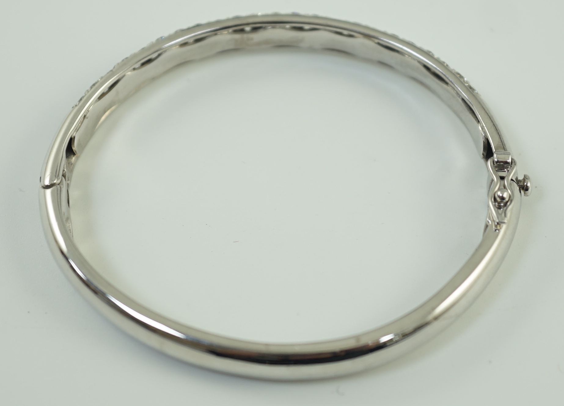 A modern 18ct white gold and pave set diamond hinged bangle